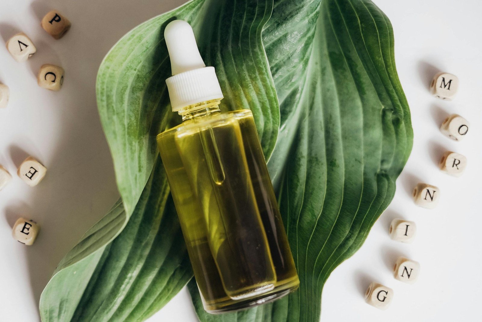 A bottle of organic oil next to fresh green leaves highlighting natural beauty care