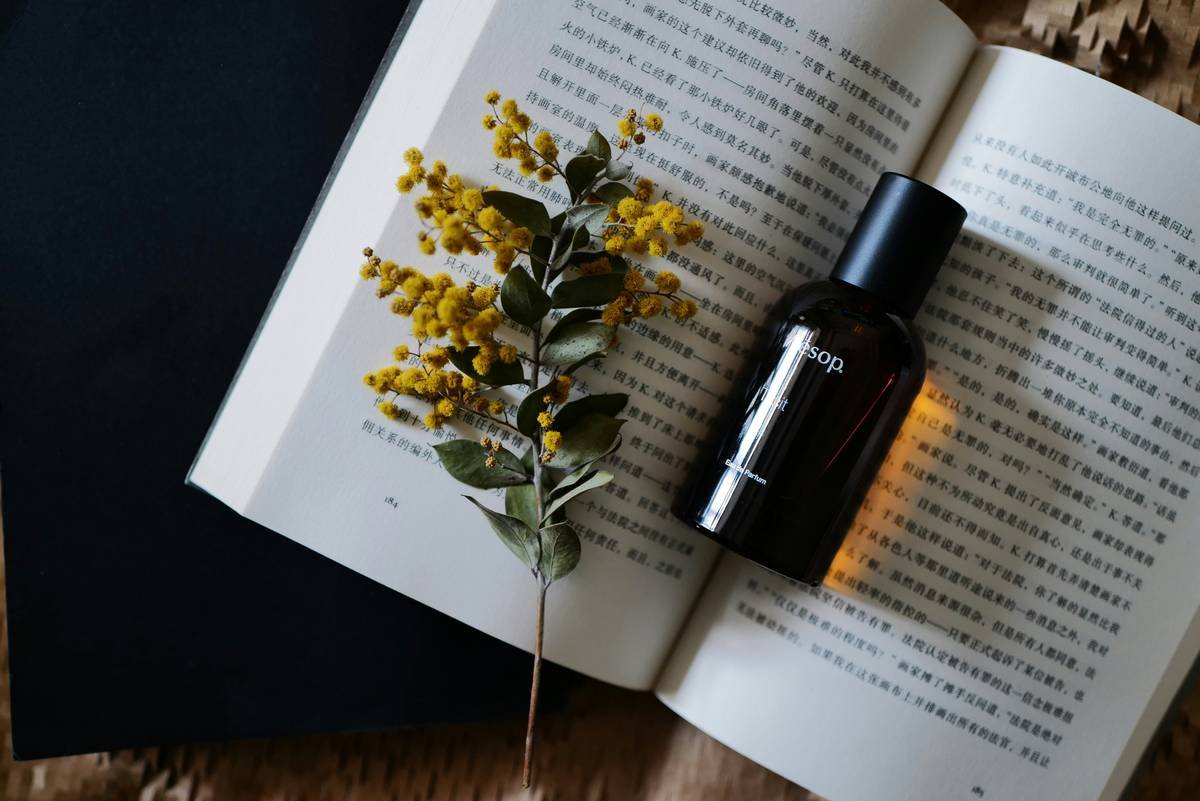 A bottle of lavender essential oil surrounded by dried flowers on a wooden table