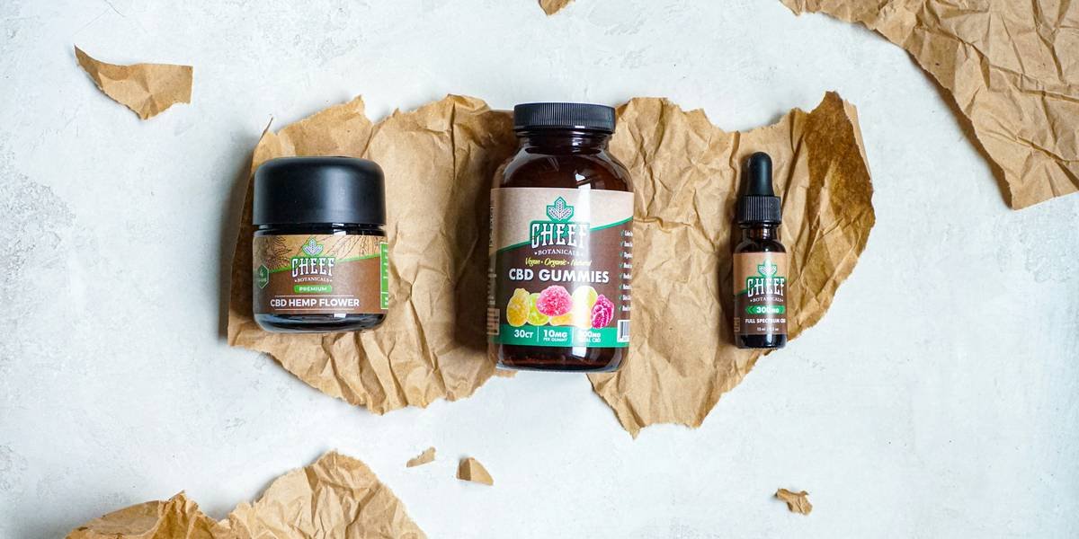 A bottle of organic canola cooking oil sitting on a wooden table next to fresh herbs